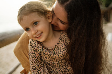 Mother and daughter on the beach, laugh and hug each other. Smiling family enjoy vacation on the...