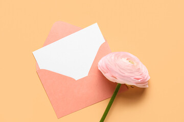 Envelope with blank card and pink ranunculus flower on beige background