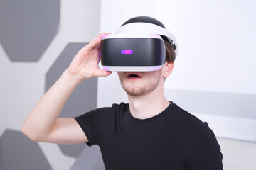 Portrait of happy young handsome man, positive smiling guy using, wearing a modern device virtual reality headset mask or 3D, AR, VR glasses, playing the game. People and technology metaverse concept