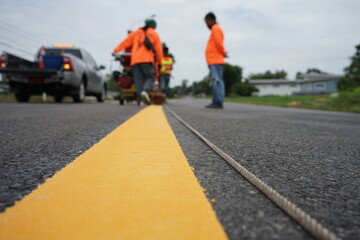 Blurred image of yellow traffic marking work on paved road