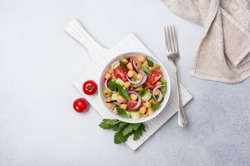 Healthy vegetarian salad with cooked chickpeas, parsley, cherry tomatoes, onion, fresh cucumber and...
