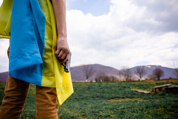 A man holds a weapon in his hand against the background of the Ukrainian flag.