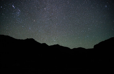 Horizontal shot of starry night sky with mountain silhouette in Chile