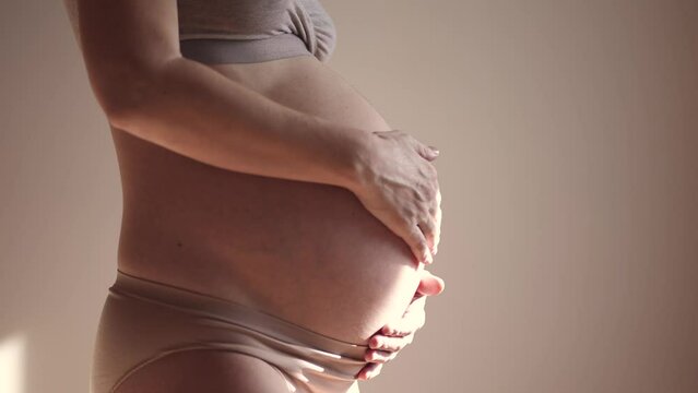 pregnant woman. health pregnancy motherhood procreation concept. close-up belly of a pregnant woman. woman waiting for a newborn baby indoors. pregnant woman holding her belly sunlight