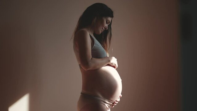 pregnant woman indoors. health pregnancy motherhood procreation concept. close-up belly of a pregnant woman. woman waiting for a newborn baby. pregnant woman holding her belly sunlight