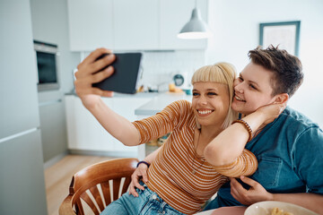 Carefree female couple taking selfie with cell phone at home.
