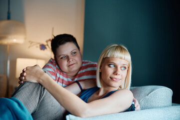 Young lesbian couple enjoys while relaxing on sofa at home.