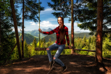 Girl with long hair on forest swing with beautiful mountain view