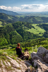 Fototapeta premium Friendship between man and dog.. Young girl siitting on top of the hill with her dog Bandog and looking on mountains