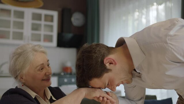 Young man kissing his old mother's hands during the feast (Ramadan or Şeker Bayram). People who follow Muslim traditions.