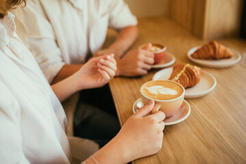 Happy couple in love drinking coffee with croissants, sitting in a coffee house.