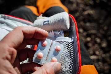 Pink tablets close-up, a person's hand holds medications. First aid for poisoning in a hike, a...