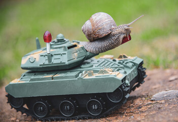A garden snail climbed onto a green toy tank.