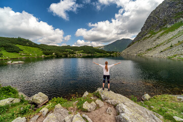 Fototapeta na wymiar Girl tourist standing and looking on beautiful nature with lake and summer mountains in Western Tatras in Slovakia
