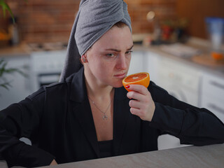 Sick woman trying to sense smell of fresh orange, has symptoms of Covid-19, corona virus infection....