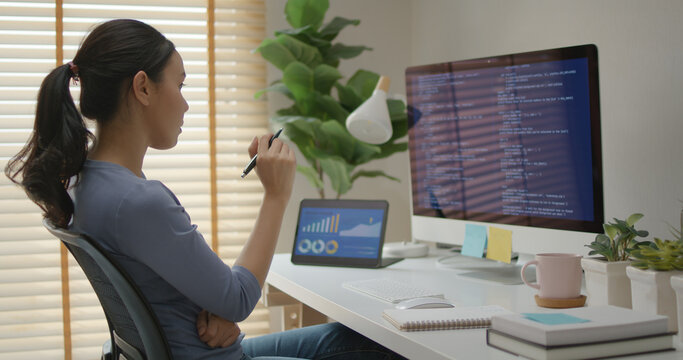 Asia young business woman sit busy at home office desk work code on desktop PC reskill upskill for job career remote self test IT deep tech ai design skill online html text for cyber security.