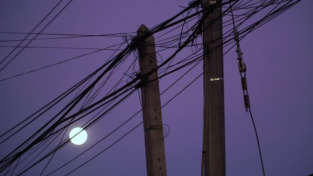 Messy Exposed Power Lines In Poor Third World Country At Night. Moon In Background