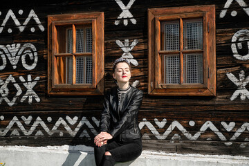 Young pretty girl posing in front of old wooden rural cottage in village Cicmany in Slovakia