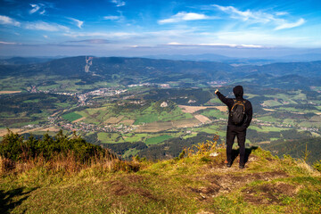 Fototapeta na wymiar Hiker on top of the hill Velky Choc and showing on country landscape in Slovakia