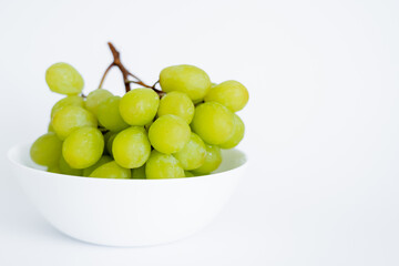 fresh and green grapes in bowl on white.