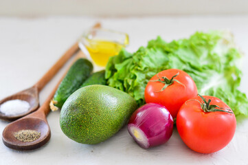 Fresh vegetables - avocado, tomato, red onion, cucumber, lettuce. Light background.