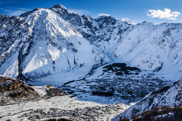Obraz premium Mountain landscape with the Georgian ancient village of Kazbegi Stepantsminda located in the lowland is located in the Caucasus Mountains, near Mount Kazbek, near the Russian-Georgian border