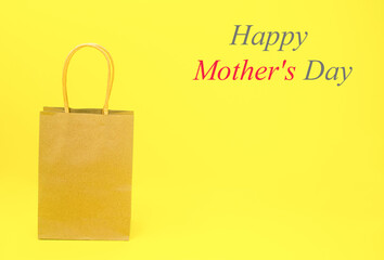 A paper bag with the words Happy Mother's Day , in gray and red, on a yellow background. The concept of a gift for mom, surprise, discounts, sale, care. High quality photo