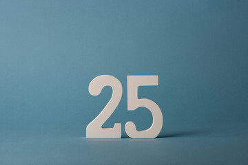 White wooden number twenty-five 25 on blue background.