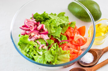 Salad of avocado, tomato, onion and lettuce. Light background.