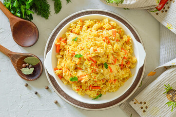 Appetizing pilaf in a white plate on a light background. Rice with vegetables and meat.