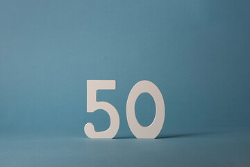 White wooden number fifty 50 on blue background.