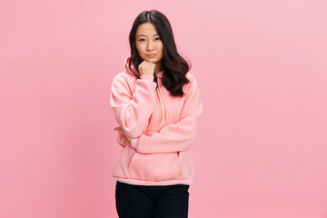 Awesome lovely cheerful happy Asian student young lady in pink hoodie sweatshirt folds hands posing isolated on over pink studio background. Good offer. Fashion New Collection concept