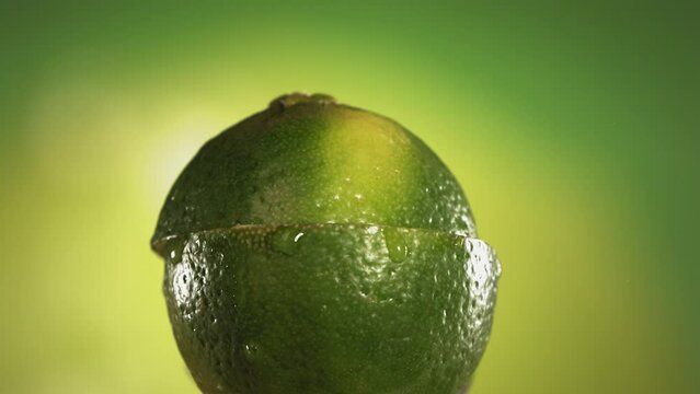 Half Lime falling and splashing on green background. Food levitation concept. Slow Motion
