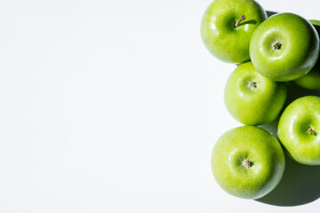 top view of stacked green apples on white.
