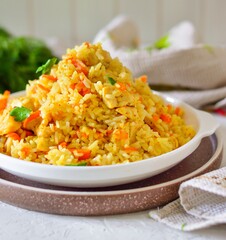 Appetizing pilaf in a white plate on a light background. Rice with vegetables and meat.