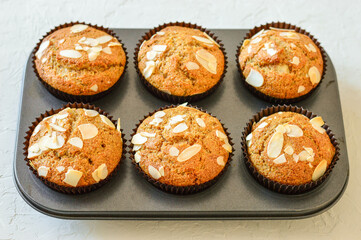 Homemade muffins. Muffins in a baking dish. Muffins garnished with almonds. Muffins on a white background.