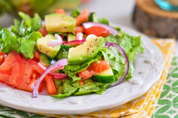 Salad of avocado, tomato, onion and lettuce. Light background.