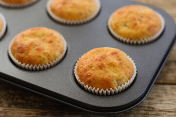 Homemade muffins. Muffins in baking molds. Muffins on a wooden background.