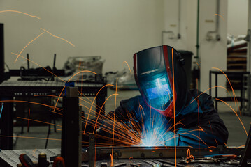 Professional Heavy Industry Welder Working Inside factory, Wears Helmet and Starts Welding....