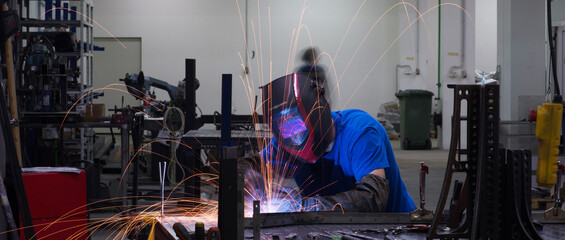 Fototapeta na wymiar Professional Heavy Industry Welder Working Inside factory, Wears Helmet and Starts Welding. Selective Focus