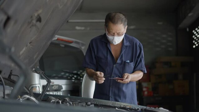 Skilled Auto Mechanic Fixing Broken Car Engine At The Garage. medium shot