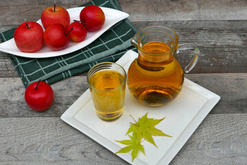 Rote Äpfel und frischer Apfelsaft im Glas und Krug auf einem Holztisch.