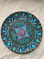 Decorative ceramic plate with  different colors. painted plate on white background, closeup, top view. Decorative porcelain plate painted with acrylic paints, dot painting