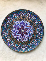Decorative ceramic plate with  different colors. painted plate on white background, closeup, top view. Decorative porcelain plate painted with acrylic paints, dot painting