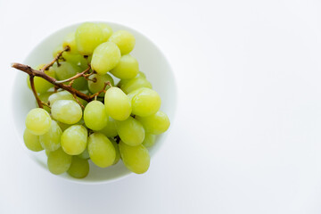 top view of green grapes in bowl on white.