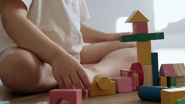 Close-up portrait of a boy building tower of block toys. Educational and creative toys and games for young children. Child development.