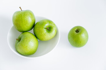 top view of green and organic apples in bowl on white.