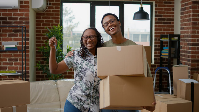 Portrait of african american couple showing apartment keys on camera, moving in first home together. Owning real estate property, buying new household on mortgage loan to move in.