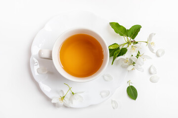 Cup of green tea on figured saucer with white apple tree flowers on white background. Top view.