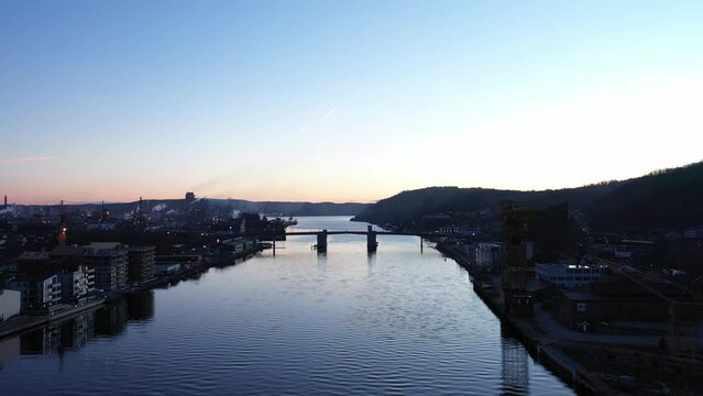 Flying above Telemark channel in Porsgrunn Norway - Silhouette of city bridge in front and Yara at Heroya industrial island in left background
